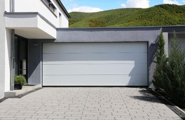 A modern garage with a clean white sectional door, professional garage door installation, servicing, repairs and replacement by Garage Door Guys Sydney