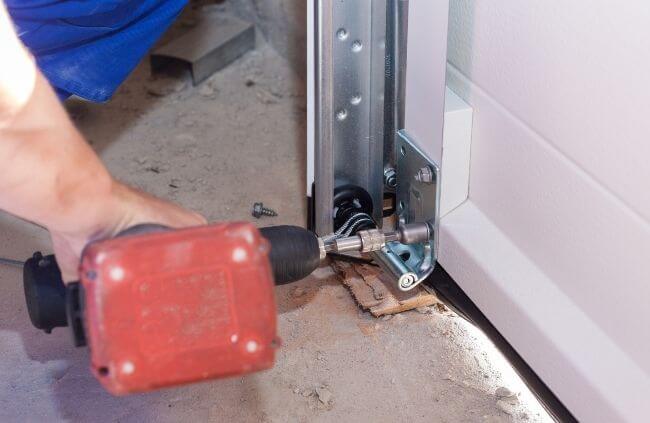 Garage Door Guys Sydney performing garage door maintenance, tightening the lower roller bracket for smoother and safer door movement.