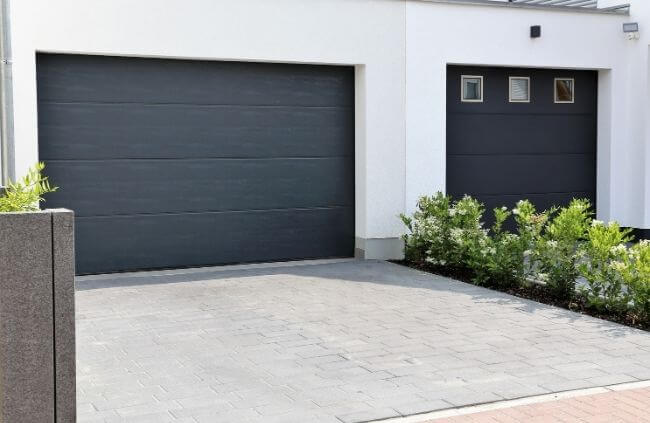 Modern double garage with sleek dark sectional doors, home service call for garage door remote replacement by Garage Door Guys Sydney.
