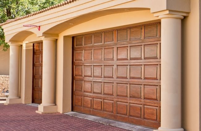 Timber look garage door replacement on a Mediterranean style home delivering a premium freshly updated finish by Garage Door Repair Guys.